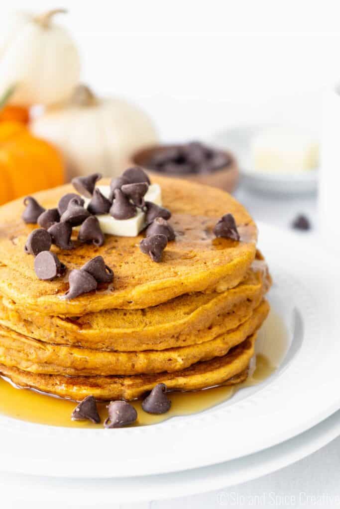 a stack of pumpkin pancakes topped with a pat of butter and chocolate chips
