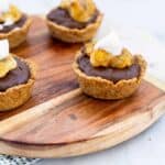 Vegan Chocolate Banana Tarts with whipped cream dollop on a wooden board