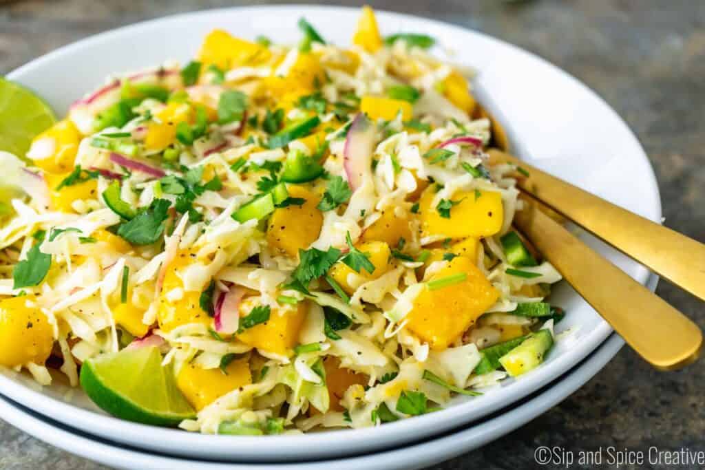 Closeup of mango slaw with limes and gold serveware