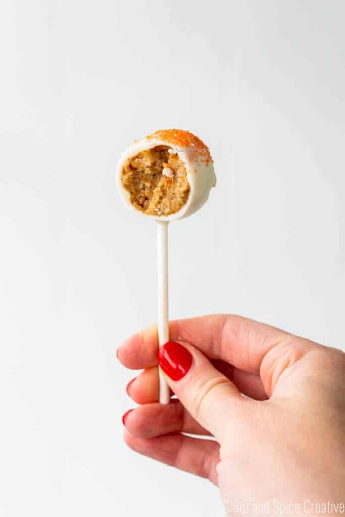 Carrot Cake Pop held in hand with 1 bite taken out