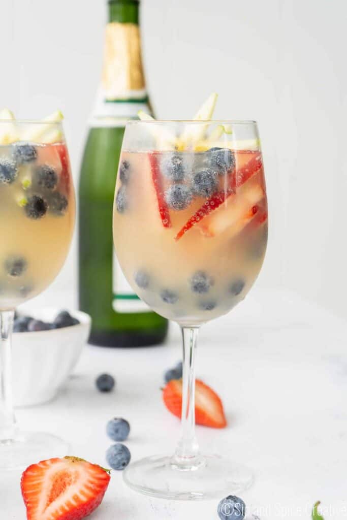 Wine glass filled with straberries, blueberries and starfruit with champagne
