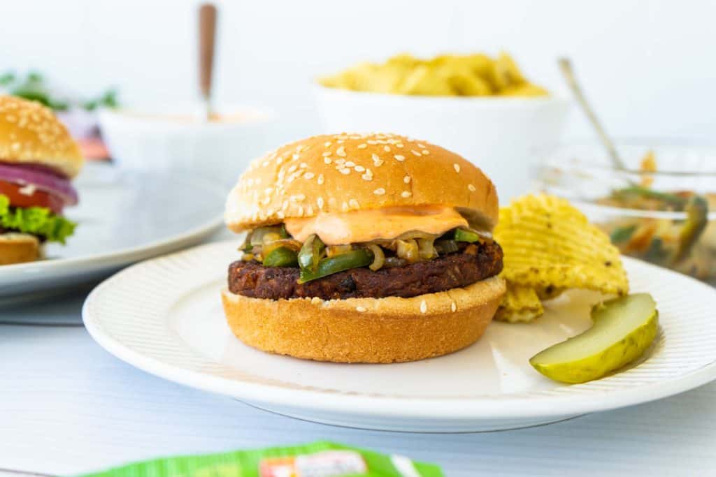 black bean burger on a sesame bun with a pickle and chips on the side