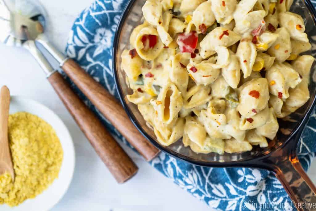 vegan mac and cheese in skillet with nutritional yeast and wooden spoons