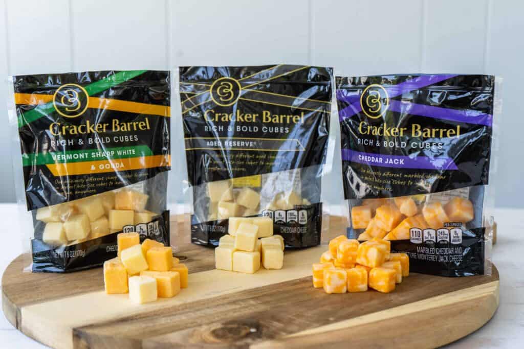 cracker barrel cheese cubes on a wooden board with their packaging