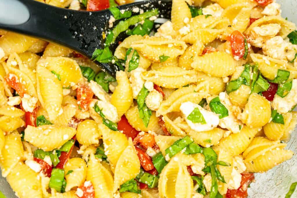 closeup of pasta salad with feta, tomatoes and fresh basil