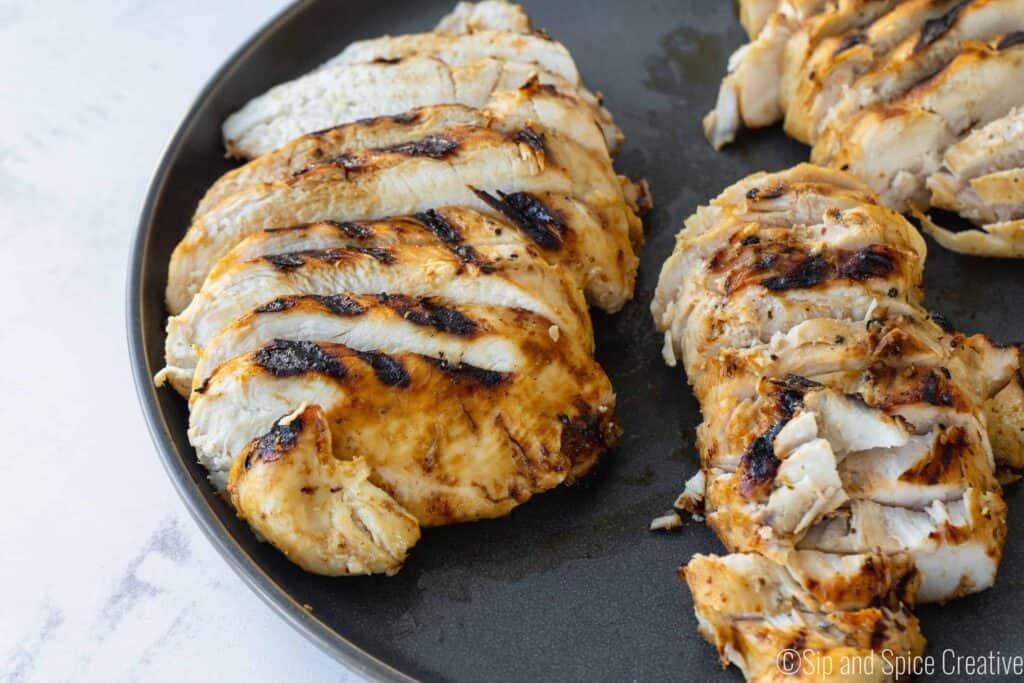 sliced grilled chicken breast on a grey plate