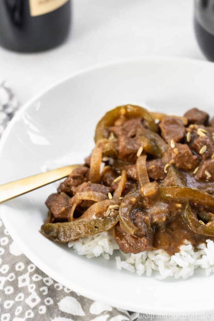 Closeup image of finished Easy Italian Pepper Steak and Rice in a white bowl of red wine