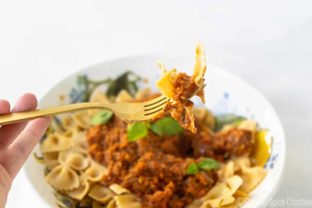 Final Image with Forkful in the air Veggie Bolognese with Fresh Basil on Chickpea Pasta