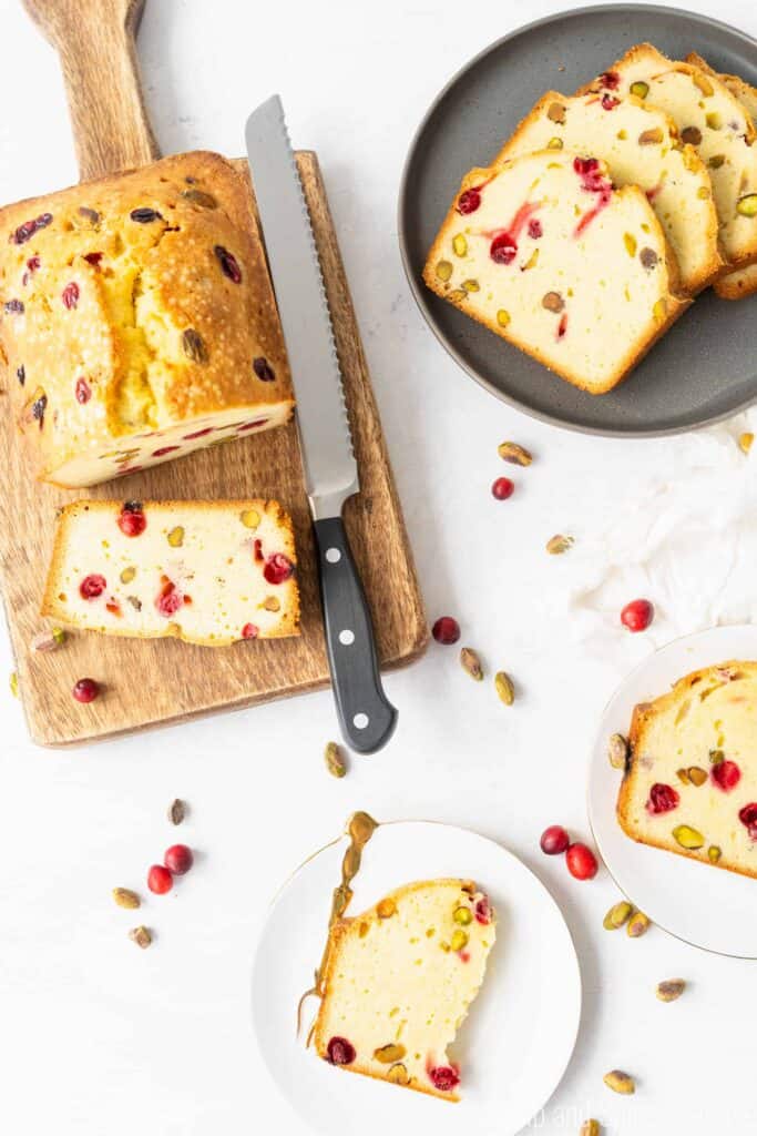 Cranberry Pistachio Pound Cake on a wooden cutting board with slices on a grey plate