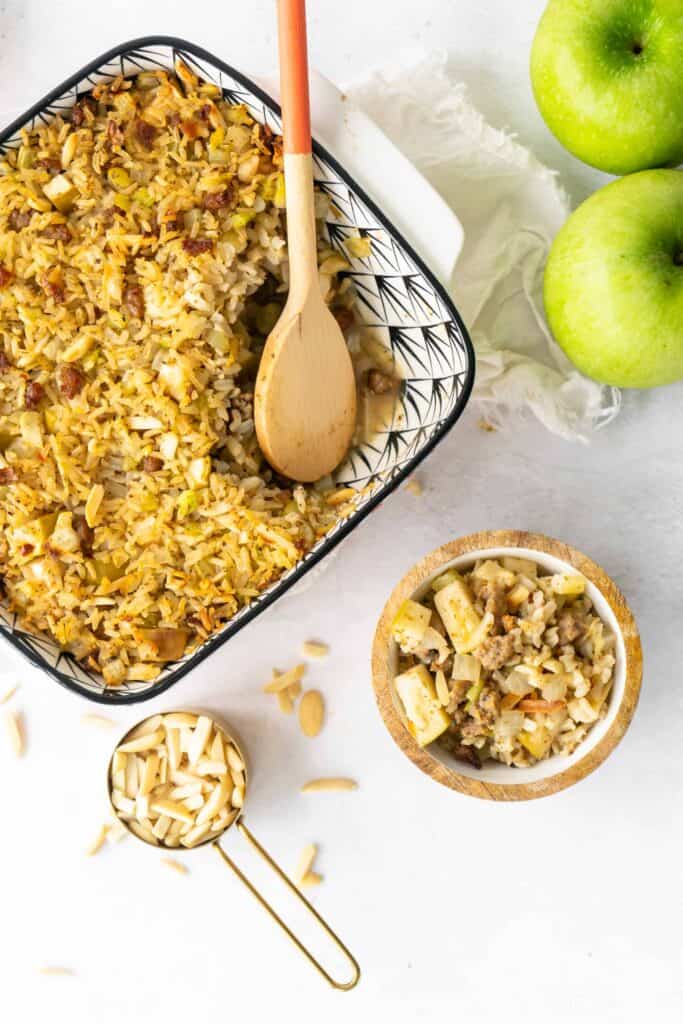 pan of Sausage and Rice Stuffing with Apples and Almonds with wooden spoon and green apples
