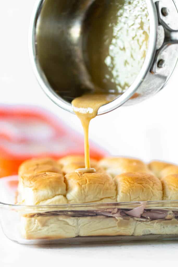mustard sauce pouring on top of monte cristo sliders in their pan