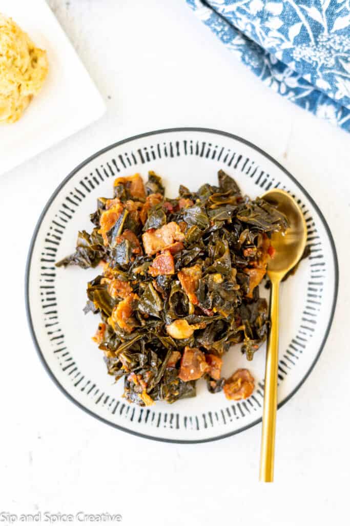 collard greens and bacon on a plate with blue edges and a gold spoon on the side