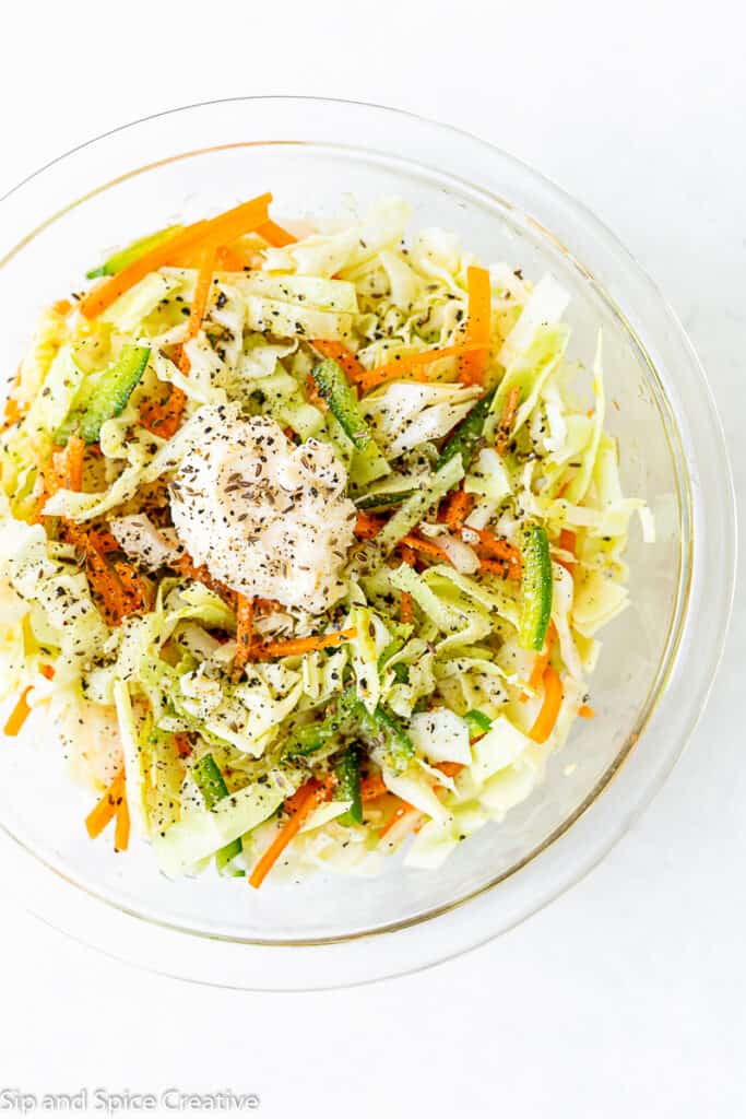 Top down view of coleslaw being prepped with a dollop of mayo and dill seeds
