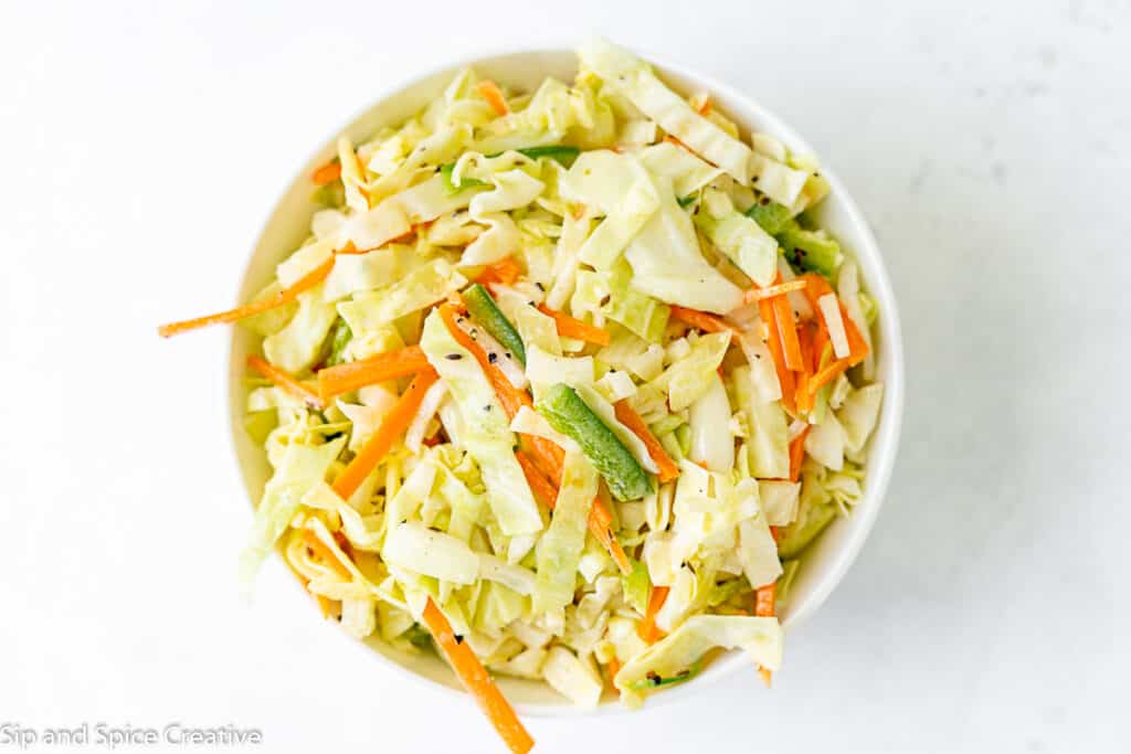 coleslaw in white bowl with visible carrots and jalapenos