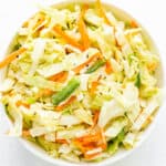Top down view of coleslaw in white bowl on white background