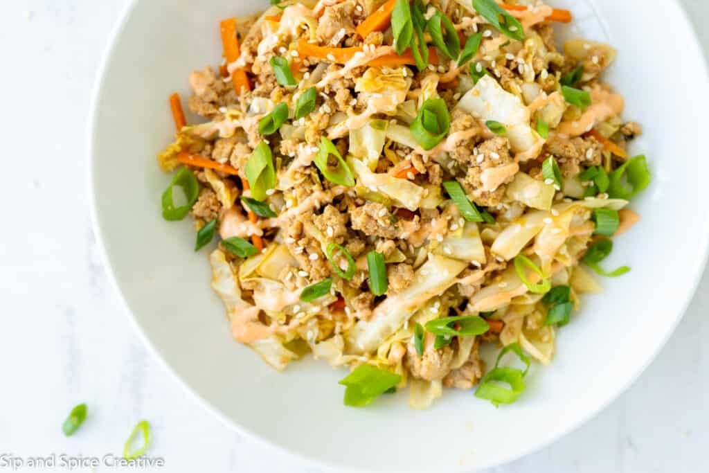 top down view of white bowl with ground turkey, cabbage, scallions, carrots