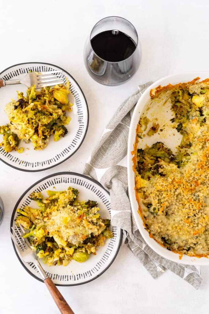top down view of white tablescape with plated and casserole dish of veggie gratin and red wine